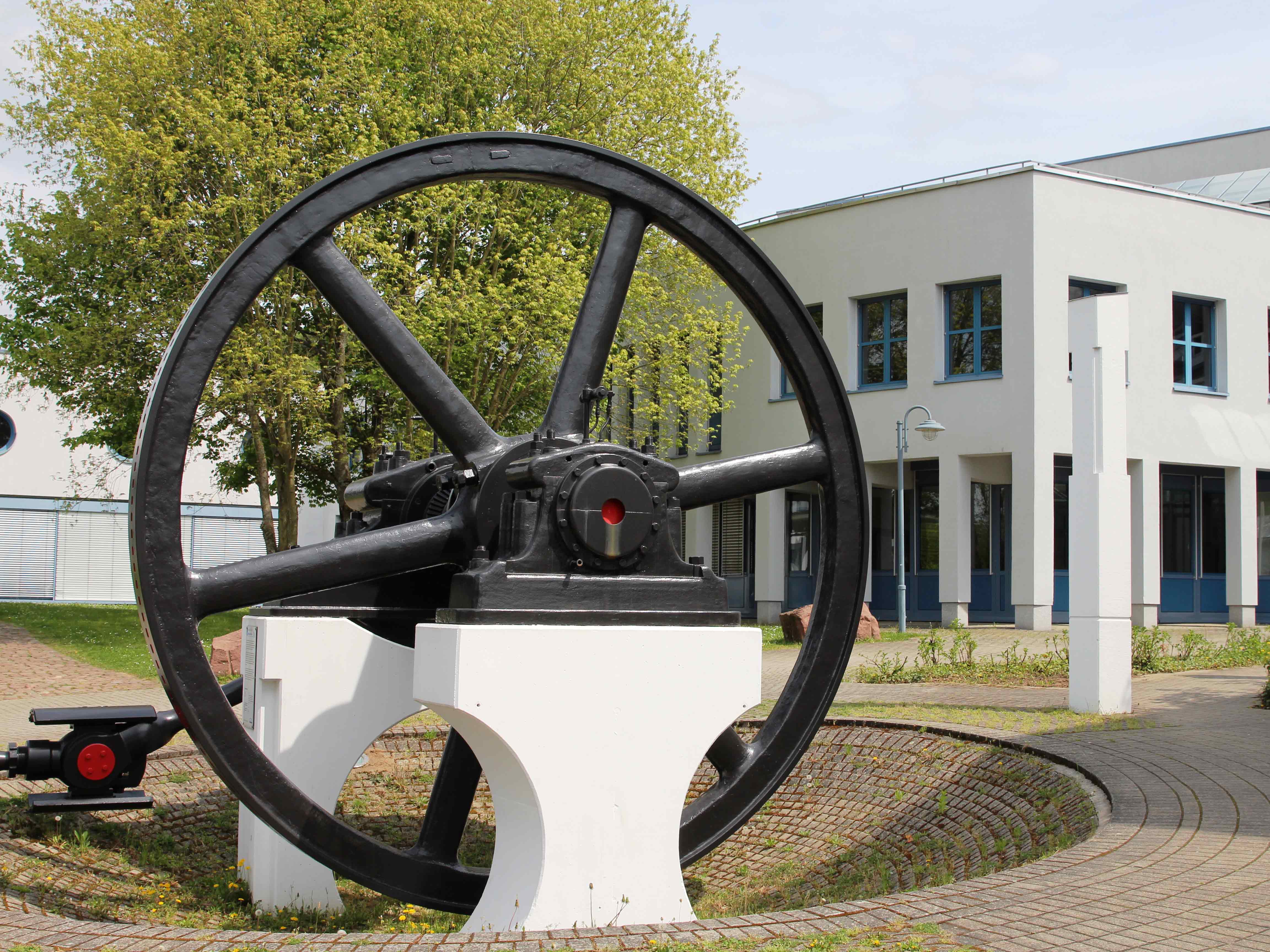 Ein schwarzes Schwungrad vor dem A-Gebäudes am Campus in Mosbach.