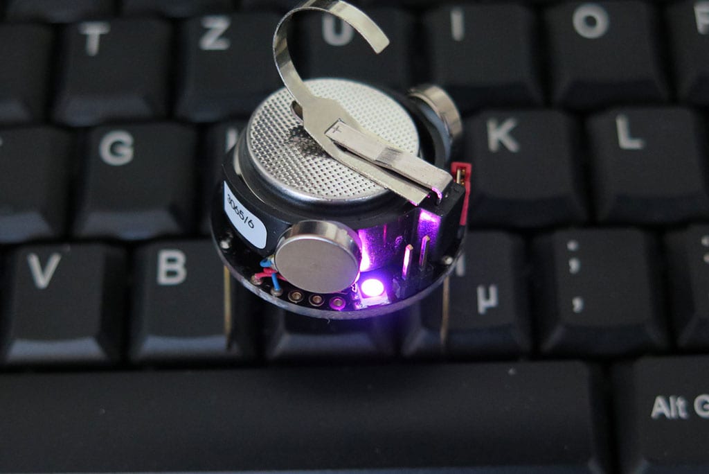 Ein lila leuchtender Kilobot auf einer Tastatur stehend