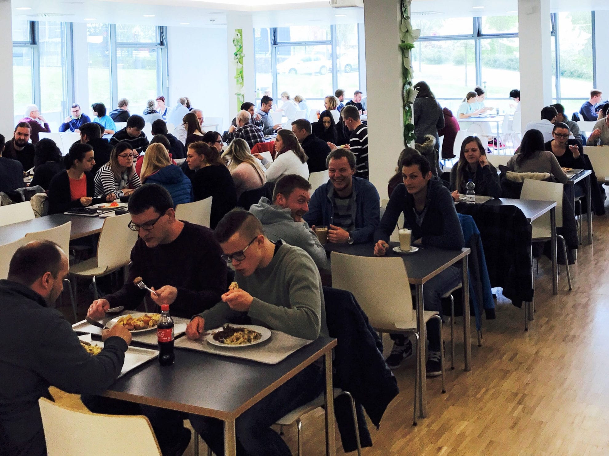 Zahlreiche Menschen sitzen in der Mosbacher Mensa im Krankenhaus an Tischen und Essen zu Mittag.